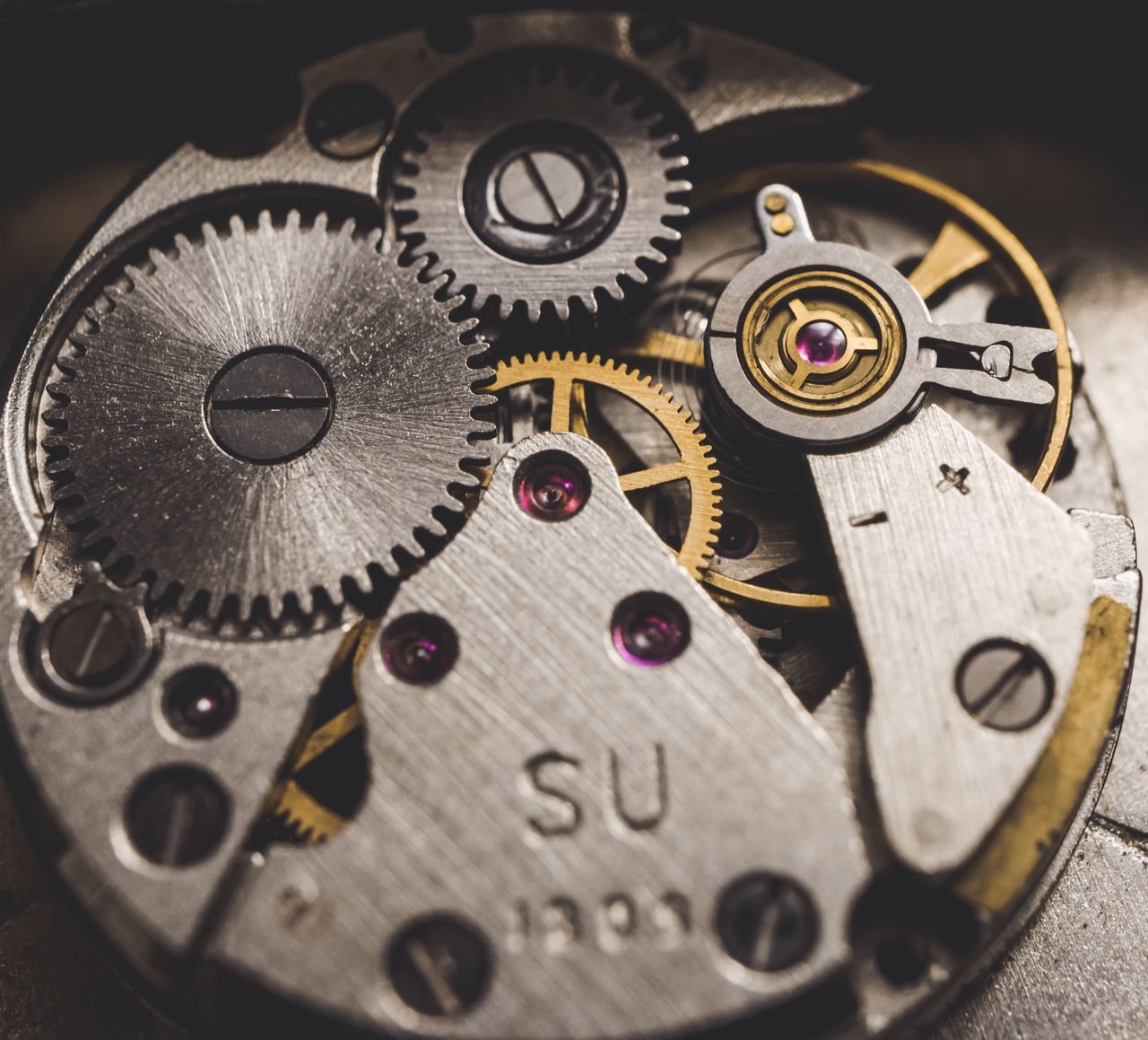 about-us Detailed view of metal gears and components in a clock, highlighting precision engineering.