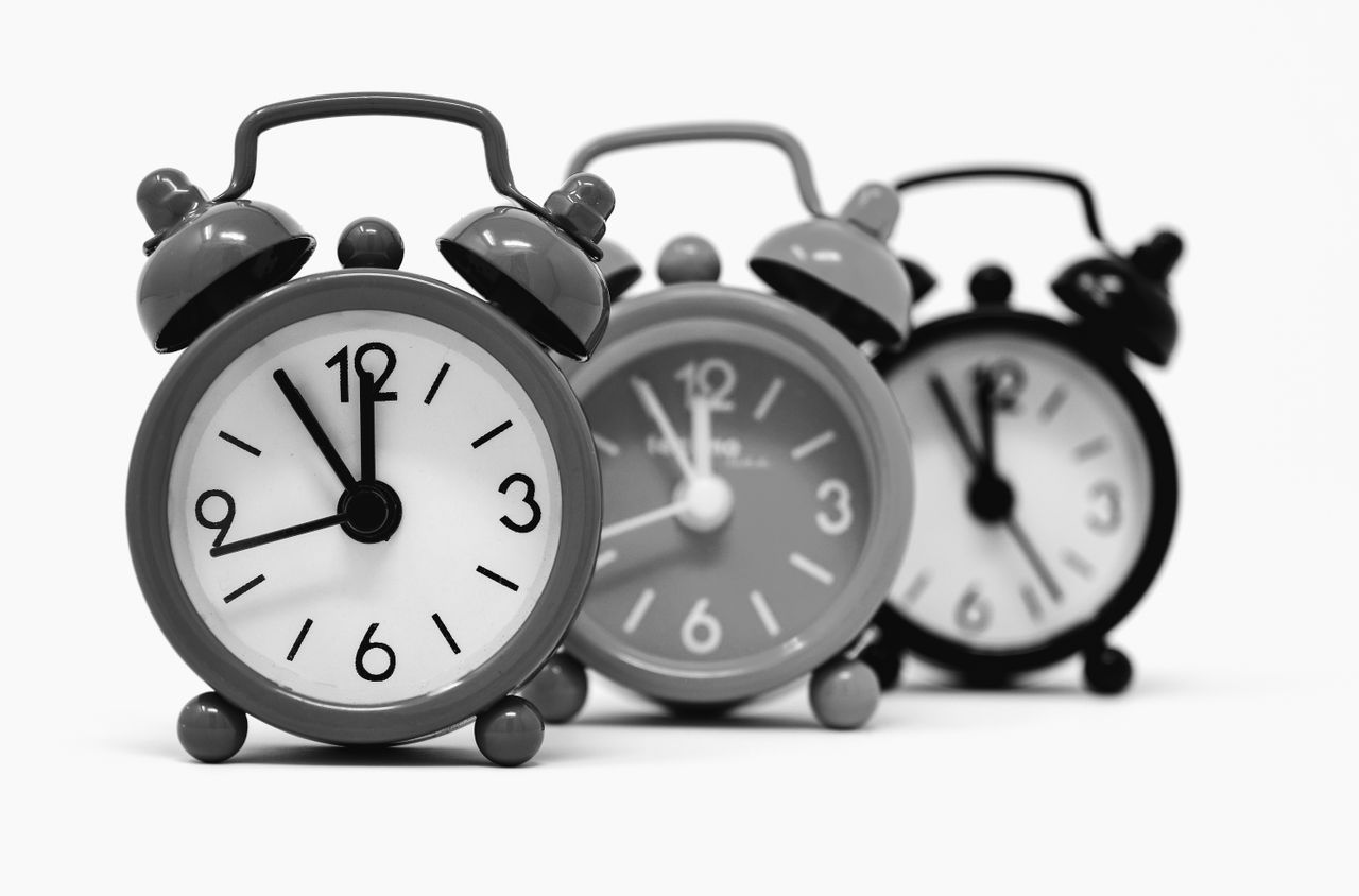 heros-img Monochrome image of three vintage alarm clocks highlighting the passage of time.